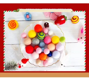 Bunte handgefertigte DIY-Wollfilzkugeln und Weihnachtsfiguren in einem weißen gewellten Teller