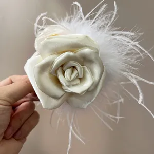 Close-up of elegant cream rose hair claw with delicate white ostrich feathers