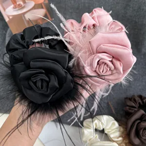 Close-up detail of luxury satin camellia flower scrunchie with elegant ostrich feather accents
