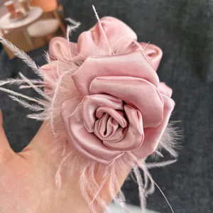 Close-up of elegant pink satin camellia hair scrunchie featuring delicate ostrich feathers