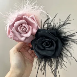 Detailed view of handmade pink and black satin rose hair clips with ostrich feathers.