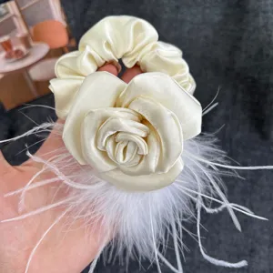 Detail of cream satin rose hair scrunchie with soft white ostrich feathers