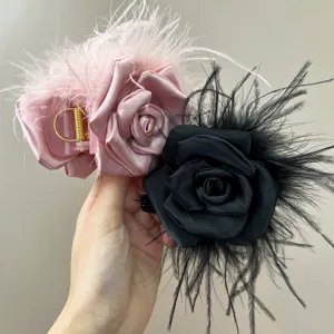 Detailed view of handmade camellia hair claw clips with satin rose and ostrich feathers