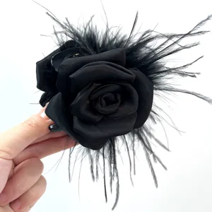 Detailed close-up of a handmade black rose hair claw clip with ostrich feathers