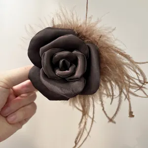 Detailed view of elegant brown satin rose hair clip with ostrich feather accents