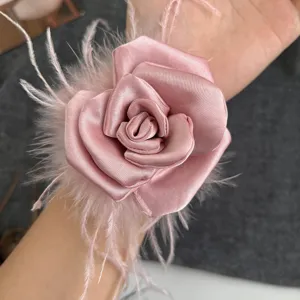 Close-up of pink handcrafted satin camellia hair scrunchie with soft ostrich feathers