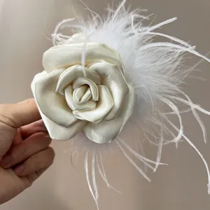 Detailed macro view of handmade cream camellia rose hair clip with elegant ostrich feathers