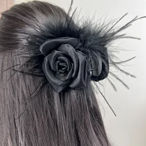 Detailed view of an elegant black hair claw clip with ostrich feathers and satin rose