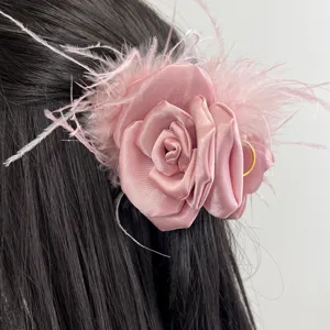 Detailed view of an elegant pink rose fabric hair clip with soft ostrich feathers