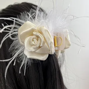 Close-up of elegant cream fabric rose hair claw clip with white ostrich feathers
