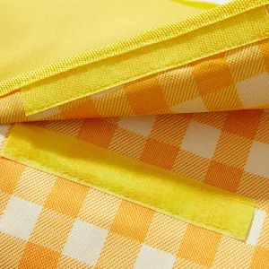 Close-up detail shot of the yellow and white gingham picnic blanket fabric and velcro strap.
