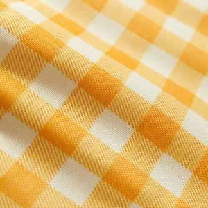 Close-up of yellow and white checkered picnic mat fabric, showing waterproof texture details.