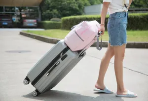 Portable foldable travel duffel bag with trolley sleeve shown outdoors on rolling luggage.