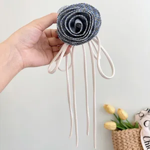 Primo piano di un fermaglio per capelli a rosa scozzese blu con lunghi nastri bianchi.