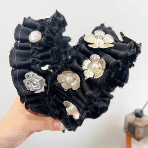 Detail van een elegante zwarte geplooide hoofdband met gouden bloemen en parels