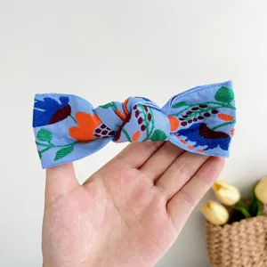 Détail montrant la broderie florale complexe sur une pince à cheveux bohème bleue