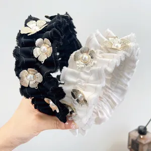 Close-up van geplooide zwart-witte haarbanden versierd met gouden bloemen en parels