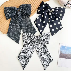 Vue détaillée de grandes pinces à cheveux à nœud avec motifs à pois et léopard chic