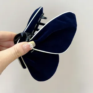 Gros plan sur l'élégante pince à cheveux papillon en velours bleu marine avec bord blanc