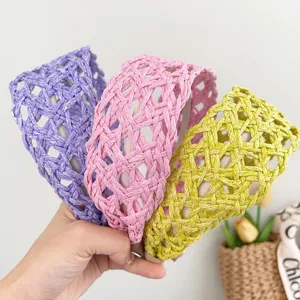 Close-up of three woven wide-brimmed hairbands in purple, pink, and yellow holiday style