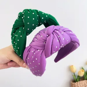 Detailopname van groene en paarse geknoopte haarbanden met fonkelende strass-steentjes.