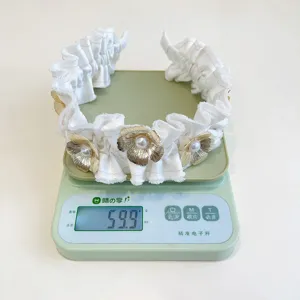 Detailweergave van witte geplooide bloemenhoofdband die 59,9 gram weegt op schaal