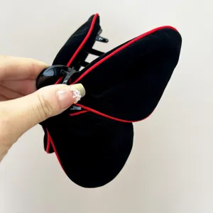 Gros plan sur pince à cheveux papillon en velours noir avec bordure rouge