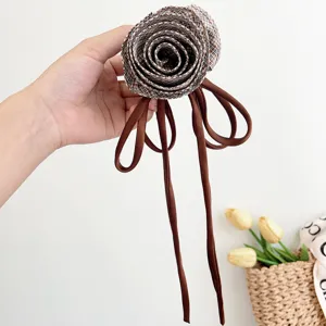 Dettaglio di un fermaglio per capelli in tessuto a rosa scozzese con lunghi nastri.