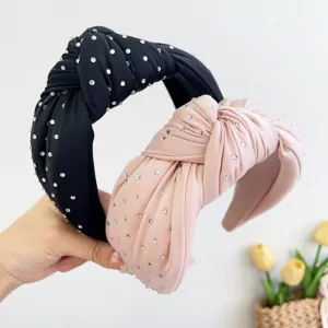 Detail van elegante geknoopte stoffen haarbanden met fonkelende strass in zwart en roze.