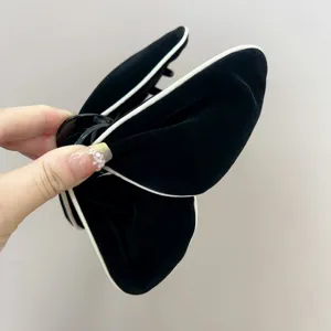 Gros plan d'une pince à cheveux papillon floquée noire avec bordure blanche chic