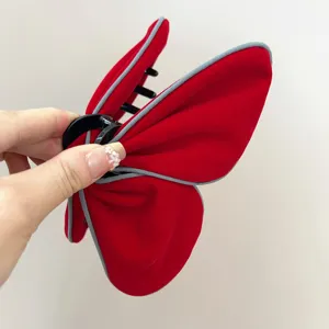 Gros plan d'une pince à cheveux papillon en velours rouge avec bordure contrastée