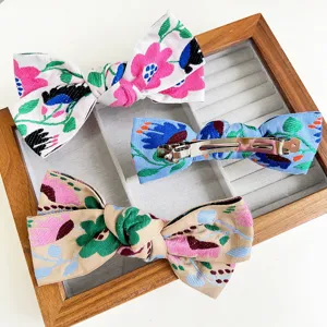 Gros plan de barrettes à nœuds brodés bohèmes aux motifs floraux exquis et clip en métal.