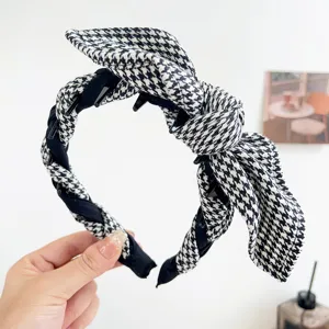 Detailed close-up of a black and white houndstooth headband with a knotted bow.