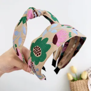 Détail d'un bandeau large brodé bohème avec des motifs floraux colorés et un nœud central