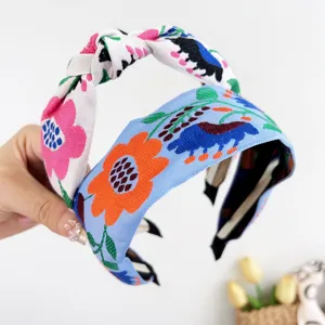 Détail de serre-têtes brodés bohèmes avec motifs floraux et nœud central élégant.