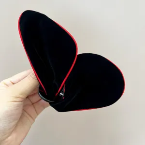 Gros plan sur la pince à cheveux papillon en velours noir avec liseré rouge élégant