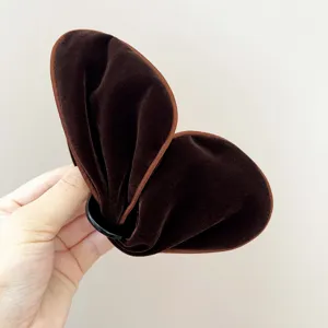 Vue détaillée de la texture velours doux d'une pince à cheveux marron en forme de papillon