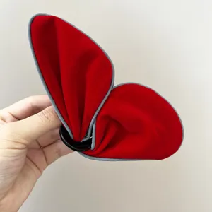 Détail macro d'une pince à cheveux papillon en velours rouge avec une bordure grise