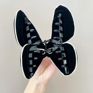 Détail d'une pince à cheveux papillon floquée noire montrant la structure interne.