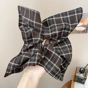 Close-up of a retro brown plaid pleated oversized fabric hair scrunchie accessory