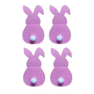 Vue détaillée de quatre porte-couverts de Pâques en feutre rose en forme de lapin.