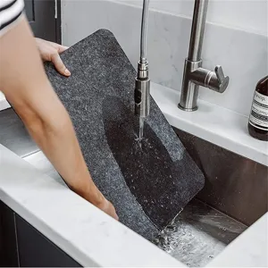 Graues Filz-Platzset wird unter dem Wasserhahn gereinigt, um Waschbarkeit zu zeigen