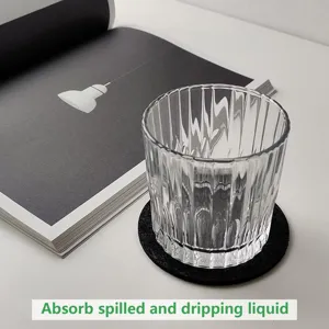Close-up detail of a black circular felt coaster absorbing liquid under a glass water cup