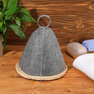 High-quality detail shot of a grey felt sauna hat with a braided straw base on wood