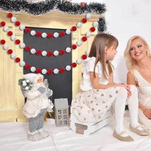 Red and white wool pom pom garland decoration on a fireplace mantel for Christmas.