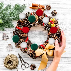Detailed view of handcrafted Christmas pine cone wreath with red green white wool pom-poms