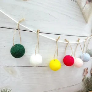 Decorative colorful wool felt ball garland bunting hung on a rustic white wooden wall background
