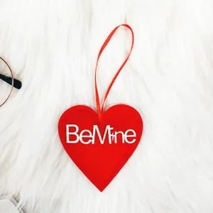 Vista detallada de un adorno de corazón de fieltro rojo con bordado 'Be Mine'