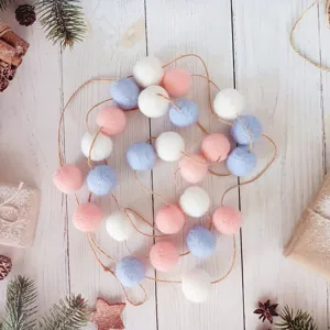 Guirlande de boules en feutre de laine pastel 3cm pour Noël sur fond de bois blanc rustique