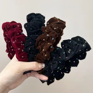 Close-up of ruffled velvet headbands with colorful glitter accents in multiple colors